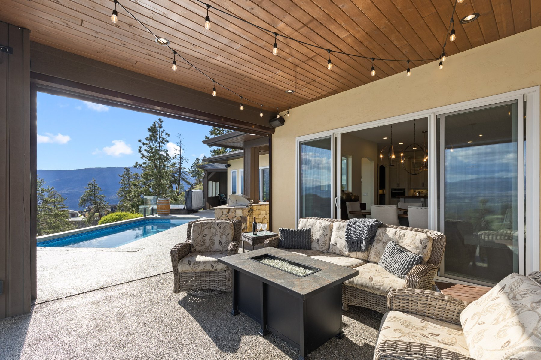Covered patio with a fire table looking out over the valley, Kelowna home