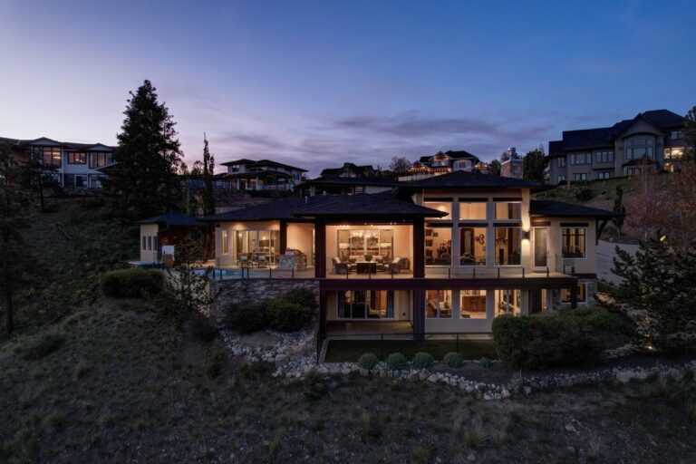 Hillside home with lit windows at twilight, Kelowna