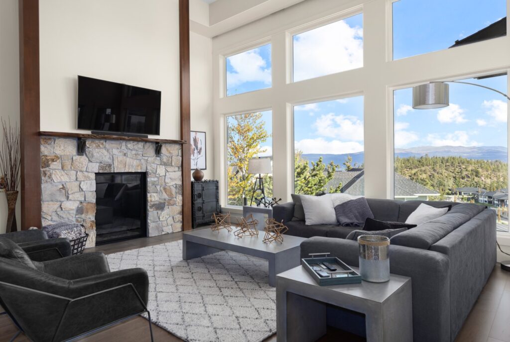 Living room with a stone fireplace and floor-to-ceiling windows facing the valley, Kelowna hillside home
