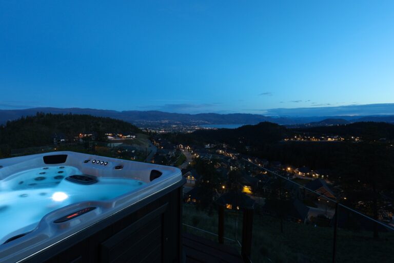 Hot tub at dusk with city lights spread out below, Kelowna hillside