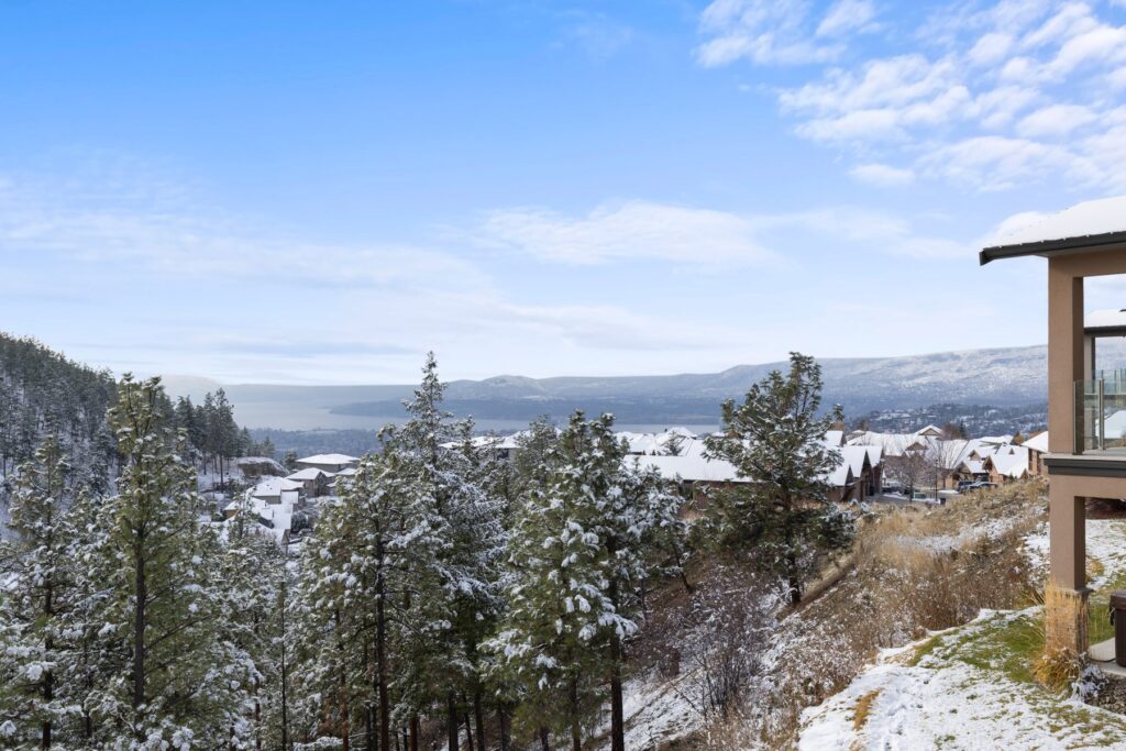 Snow-covered pines framing a winter view over Okanagan Lake from the Kelowna hillside