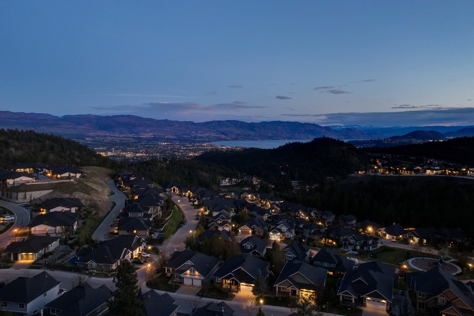 Aerial view over the Okanagan valley at dusk with town lights below, Kelowna