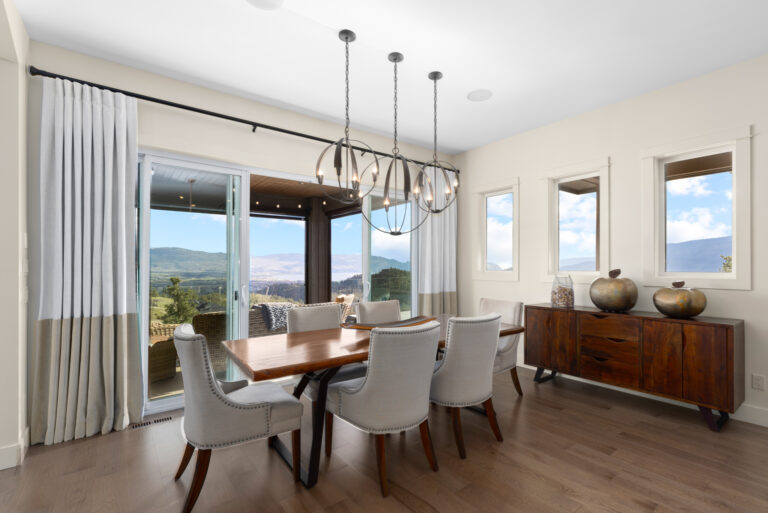 Dining room in an Upper Mission hillside home with sliding doors opening to a covered deck and a view across the valley to Okanagan Lake.