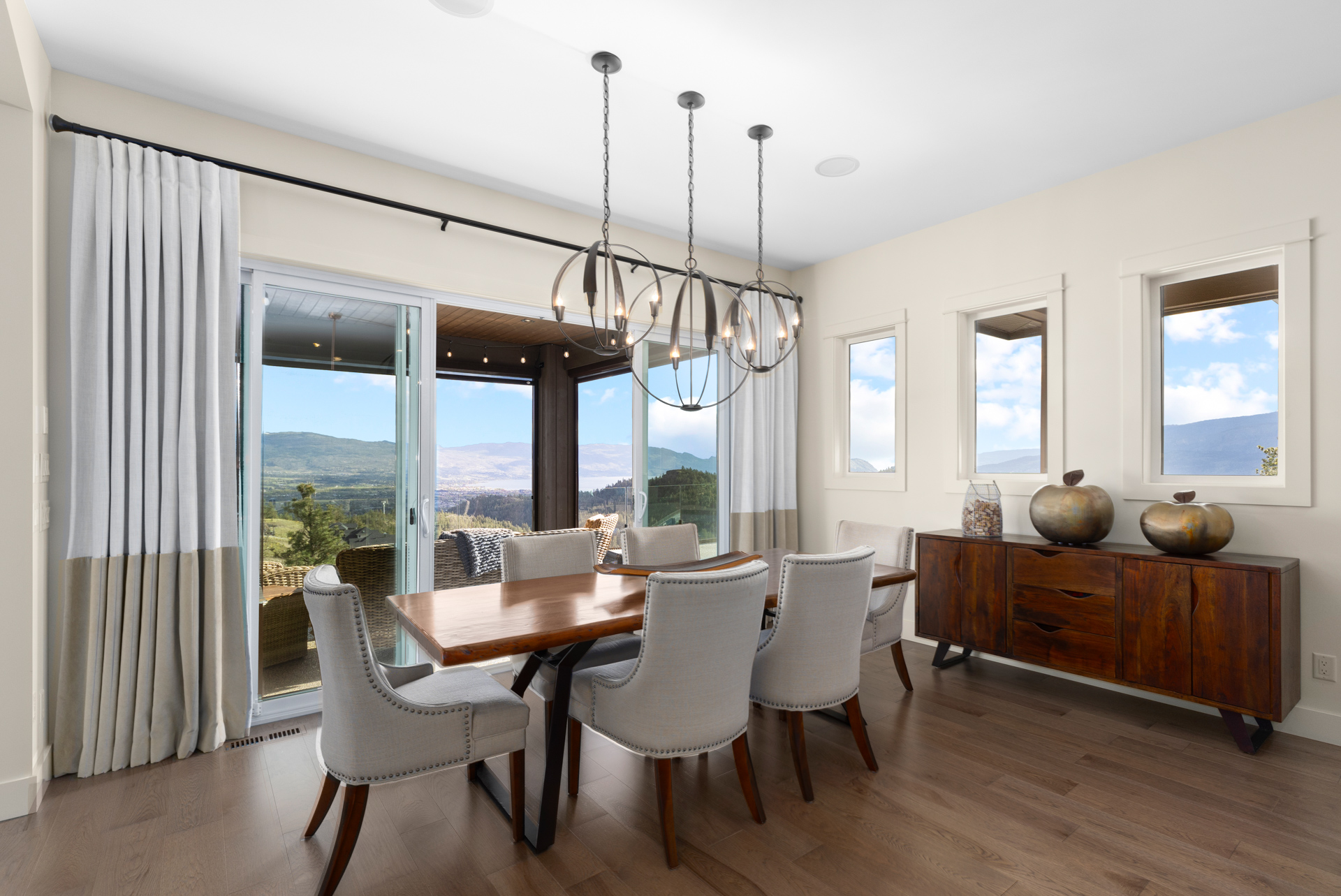 Dining room in an Upper Mission hillside home with sliding doors opening to a covered deck and a view across the valley to Okanagan Lake.