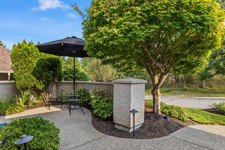 Front courtyard patio with an umbrella table and a maple tree at a Kelowna home